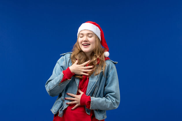 人正面图：蓝色背景上戴着红色圣诞帽的年轻女性帽子时尚表演者