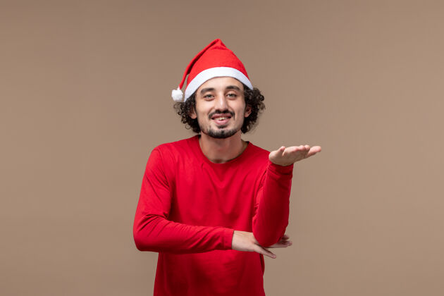 帽子正面图身着红色衣服的男性在棕色背景上微笑圣诞节孩子圣诞节男性