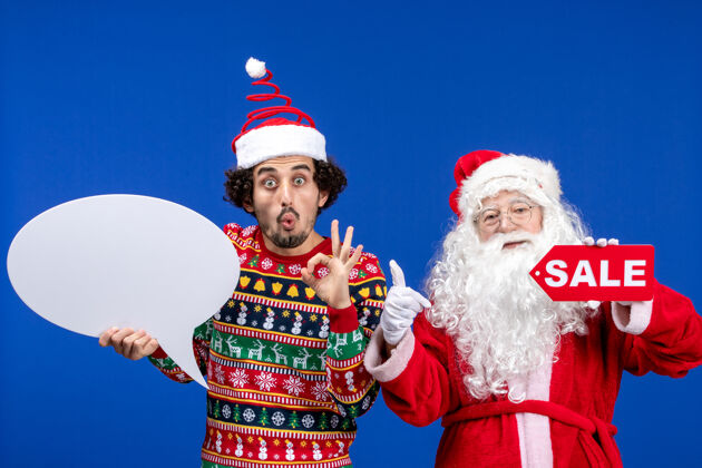 优惠前视图圣诞老人与年轻男子手持白色标志和销售文字颜色年轻圣诞节