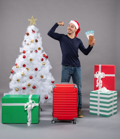 满意的男人满意的男人拿着红色的手提箱 手里拿着旅行票 在灰色的手提箱上露出胳膊上的肌肉手提箱盒子肌肉