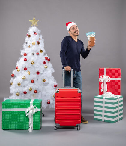 圣诞树带着手提箱和旅行票的快乐微笑的男人男人圣诞老人快乐微笑的男人