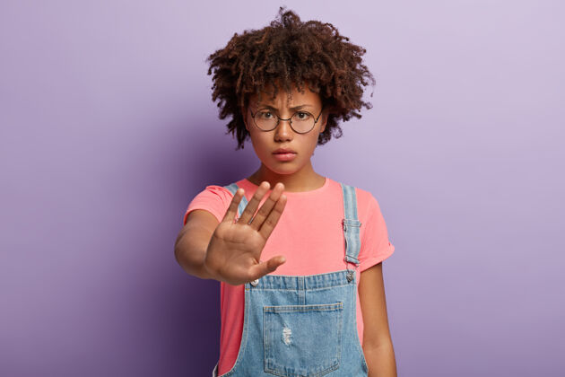 警告非裔美国妇女的照片做停止手势 有愤怒的面部表情 要求停止说话 没有任何迹象表明禁止 愤怒地看着圆眼镜 消极拒绝停止