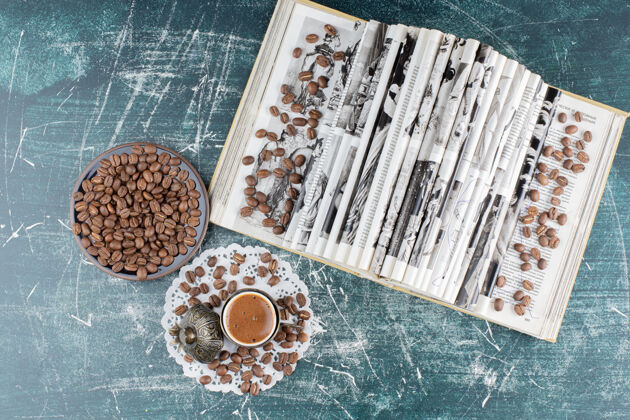 热的一杯泡沫咖啡 一盘咖啡豆和一本大理石桌上的书顶部咖啡美味