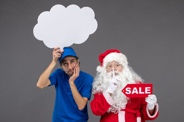 前面圣诞老人的正面图 男信使手持白云招牌 在灰色墙上出售圣诞老人十二月庆祝