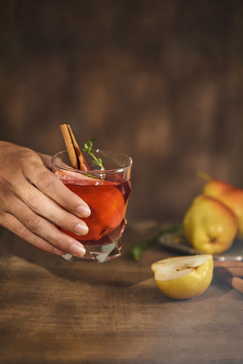 糖浆自制的热熟透的梨苹果酒和肉桂棒放在木头表面自制鸡尾酒酒精