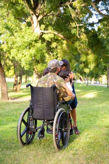 亲吻残疾退役军人父亲回家 拥抱和亲吻妻子和两个孩子后视图退伍军人或回家的概念受伤母亲团结