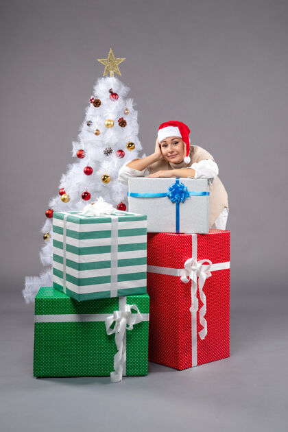 圣诞漂亮的女人在灰色的礼物周围圣诞礼物玩具包