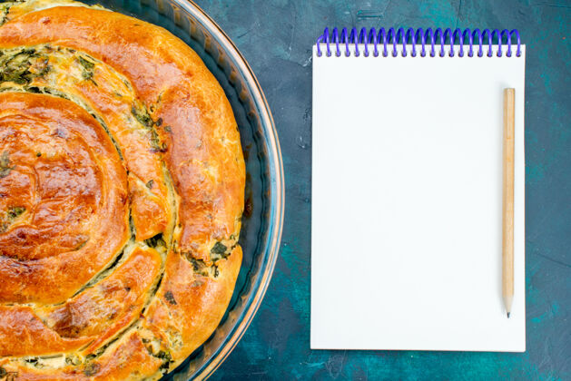 记事本在蓝色背景上用记事本烤绿色糕点蔬菜菜烘焙
