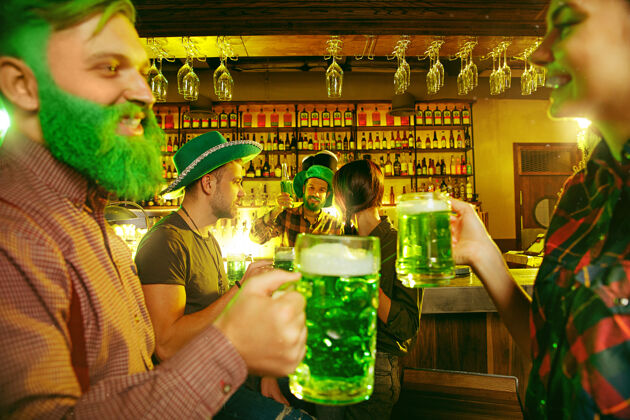 传统圣帕特里克节派对快乐的朋友在庆祝和喝绿色啤酒年轻男女戴着绿色帽子酒吧内部文化微笑帽子