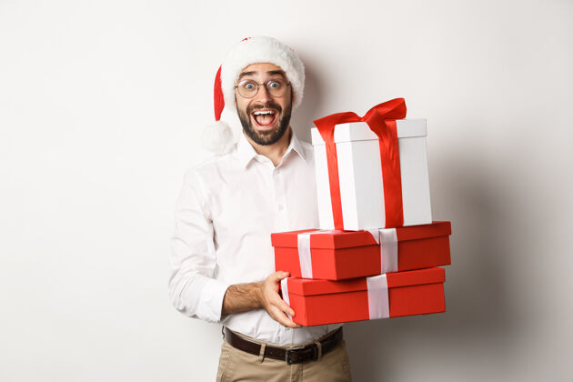 胡须寒假和庆祝快乐的家伙带来圣诞礼物 拿着礼物 戴着圣诞帽 站着快乐休闲成人