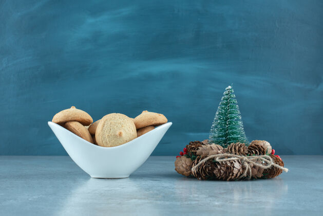 可口在树雕像旁边放一碗饼干 在大理石表面放一个花圈甜点美味美味