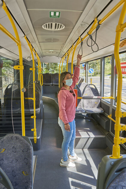 女人戴着口罩的女人坐公交车在城里旅行电车女性女孩