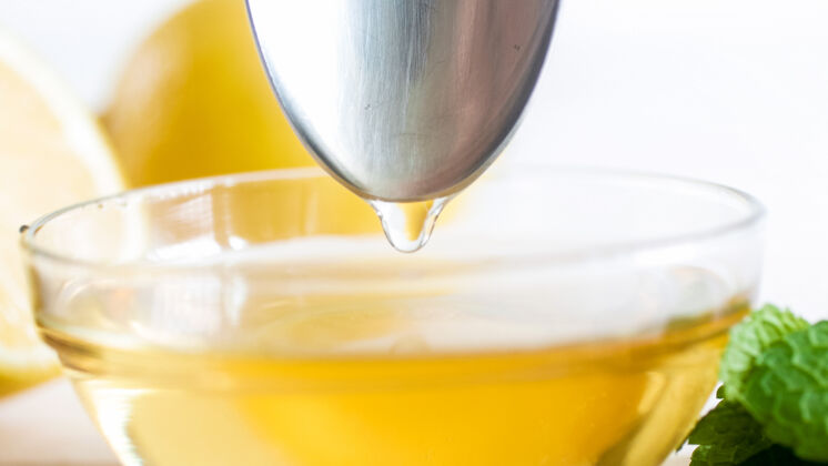 生物从蜂蜜罐里的金属勺子上掉下来的蜂蜜滴桌子粘性液体