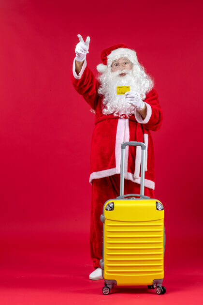 人红墙上拿着黄色银行卡的黄色袋子的圣诞老人的正视图庆祝前面圣诞