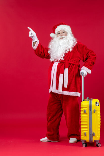 节日红墙上准备旅行的黄包圣诞老人的正视图包准备人