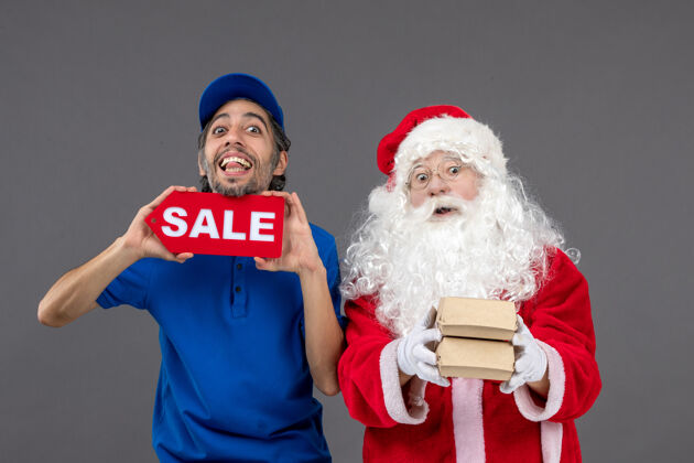 节日圣诞老人的正面图 男性信使手持销售横幅 灰色墙上挂着食品包装十二月圣诞老人圣诞老人