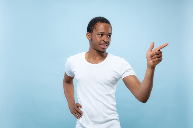 人穿着白衬衫的非洲裔美国年轻人的特写肖像指着 选择和微笑年轻人英俊选择
