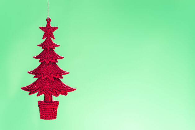 季节性一个浅绿色背景上的红色针织圣诞树衣架特写镜头工艺针织手工