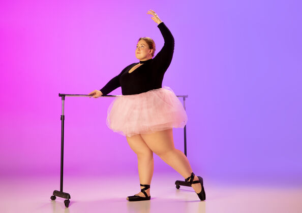 充分美丽的高加索人模特在霓虹灯下的渐变紫粉色工作室背景上练习芭蕾舞激励 包容 梦想和成就的理念值得成为芭蕾舞演员人灵感动作