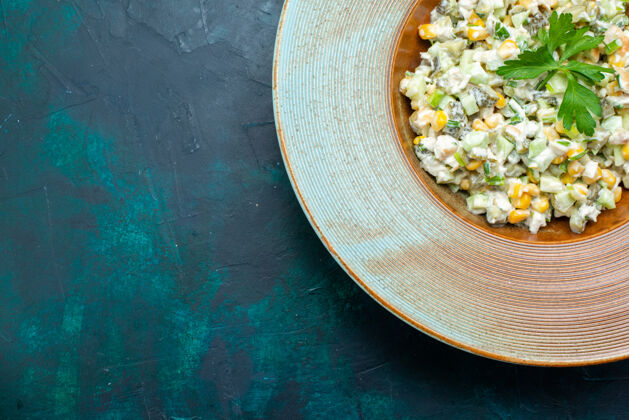 盘子在深蓝色桌子上的圆形盘子里俯瞰美味的沙拉圆形玉米深色