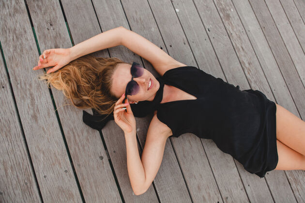 女士奢华性感迷人的女人穿着黑色连衣裙躺在地上戴着墨镜 暑假 俯瞰时尚年轻优雅