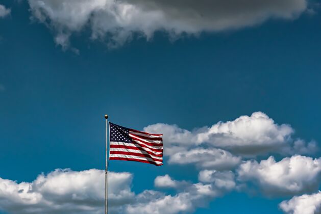 历史在多云的天空下 美国国旗在空中飘扬的特写镜头日骄傲标杆