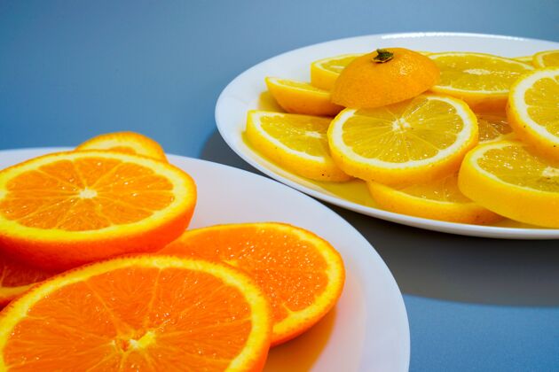 饮食在阳光明媚的日子里 把橙子和黄色柠檬放在盘子里蓝色抗氧化剂夏季