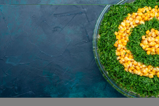 蔬菜在深蓝色桌子上的圆形玻璃盘子里放着玉米的顶视图绿色沙拉盘子食物绿色