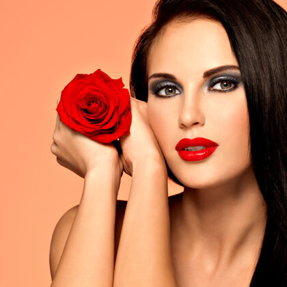 化妆品美丽的女人的肖像 明亮的时尚妆容 捧着红玫瑰黑发嘴唇玫瑰