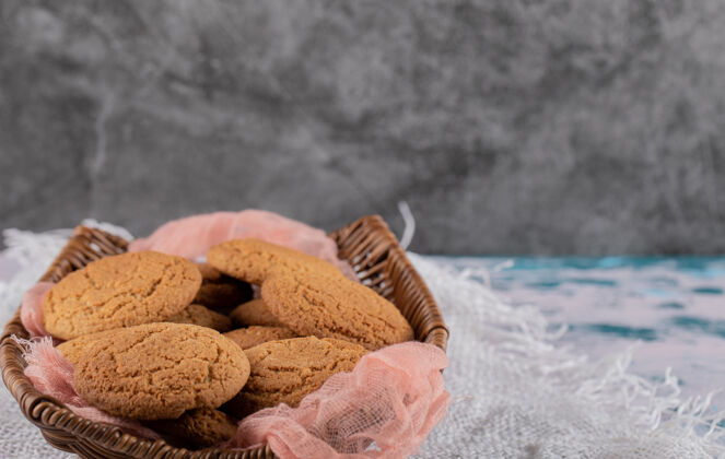 地壳放在木制篮子里的燕麦片饼干 放在粉红色的厨房毛巾上美味美味饼干