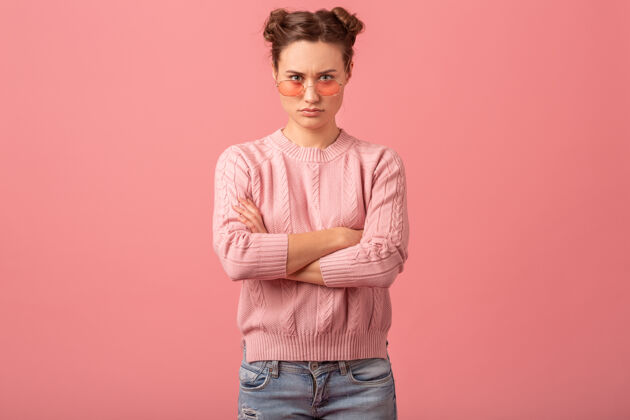 女人年轻漂亮的思考女人有一个问题 在粉红色的工作室背景下 穿着粉红色的毛衣和太阳镜看着下面摆姿势女性随意