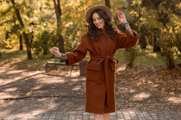 女人美丽时尚的微笑瘦身女子卷发漫步公园身着温暖的棕色外套 秋日时尚街头风女孩优雅优雅