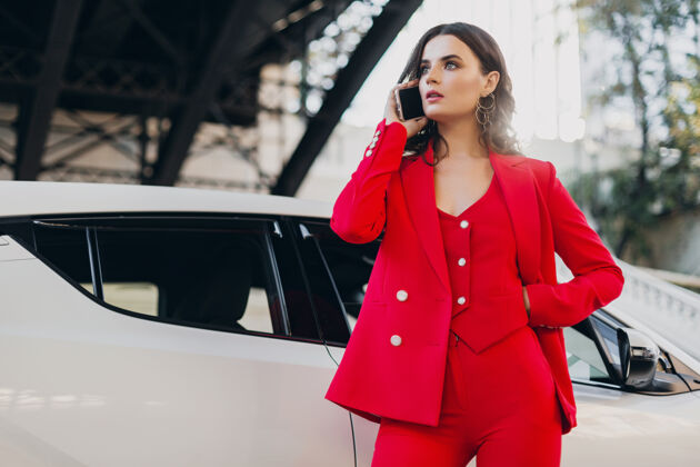 手机穿着红西装的性感美女在车前摆姿势打电话谈生意穿着汽车漂亮