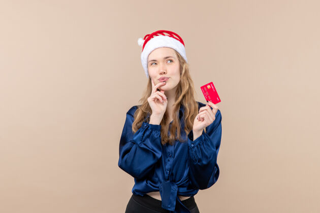 情感正面图年轻女性手持红色银行卡上一张粉色背景的钱假日新年圣诞照片情感自由的地方年轻女性肖像帽子