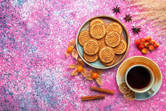 庆典盘子里甜饼的顶视图 粉红色的表面上有一杯茶饼干美味杯子
