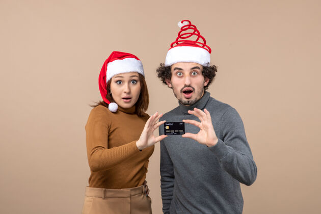 快乐圣诞心情激动满意酷酷情侣戴红色圣诞老人帽出示银行卡灰色穿着展示