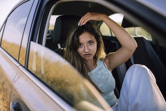 交通工具一个美丽的年轻白人女性在一个领域的汽车前排座位摆姿势的水平镜头女人汽车水平