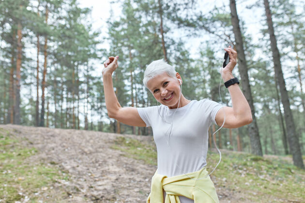 健康人 年龄 乐趣和积极的生活方式的概念快乐的中年妇女听跑步播放列表使用智能手机公园运动运动员