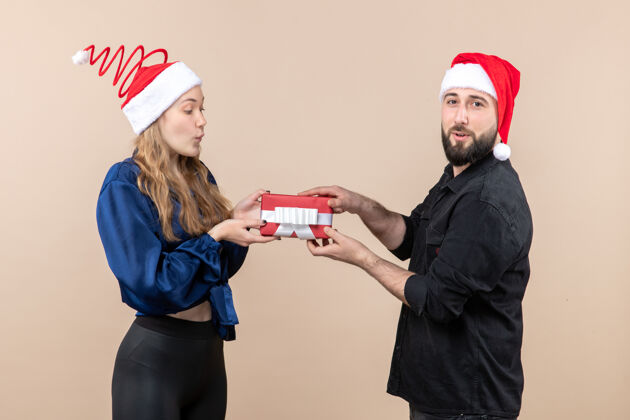 模型年轻女子和送她礼物的男人在粉红色墙上的正视图正面圣诞快乐快乐