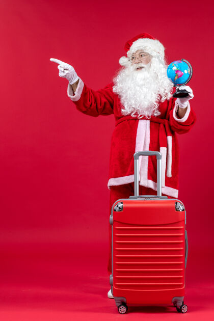 礼物圣诞老人的前视图 包里装着小地球仪 准备在红墙上旅行圣诞地球仪举行
