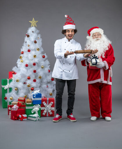 男人圣诞老人和男厨师在灰色墙上围着圣诞礼物的正视图圣诞快乐圣诞老人节日