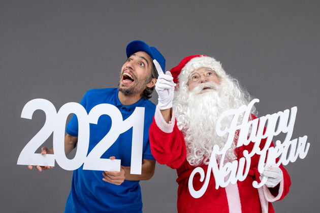 人们圣诞老人与男信使举行和新年快乐和2021年板灰墙的正面视图圣诞老人快乐人