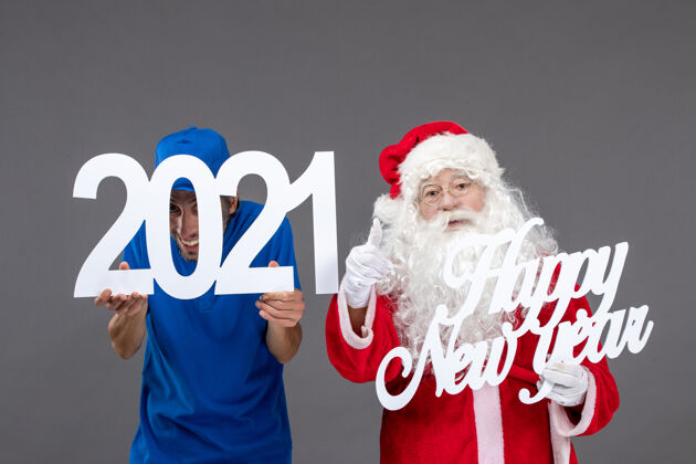 圣诞快乐圣诞老人与男信使举行和新年快乐和2021年板在灰色墙上的正面视图服装男性十二月