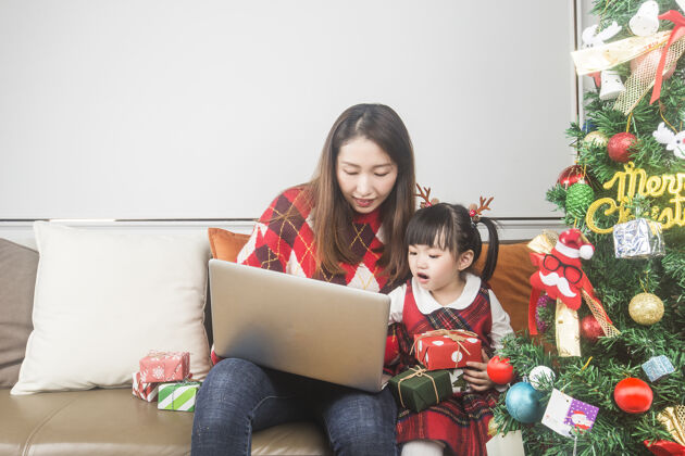 孩子快乐的妈妈和小女儿在家装饰圣诞树和礼物母亲盒子冬天