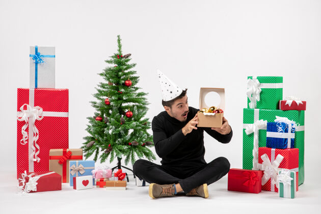 玩具正面图：年轻人围坐在白色的墙上 手里拿着圣诞礼物举行冷坐