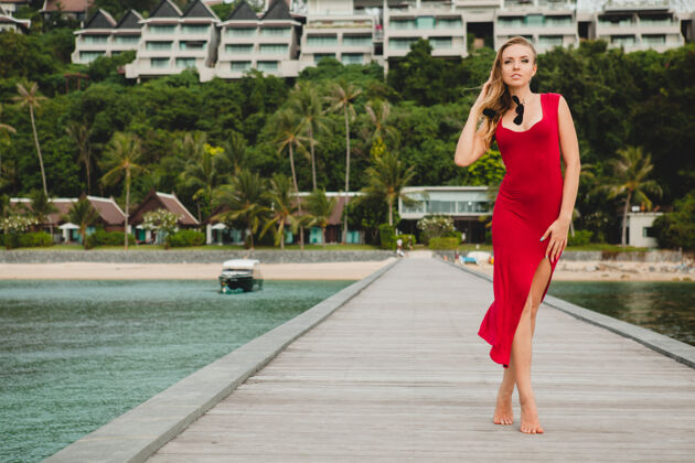 表情年轻漂亮迷人的女人独自站在豪华度假酒店的码头上 暑假 红色长裙 金色头发 性感服装 热带沙滩 诱惑 性感 微笑岛屿码头性感