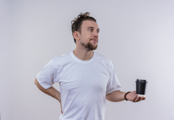 抱着看着身边穿着白色t恤的年轻人拿着一杯咖啡把手放在屁股上 背景是孤立的白色手咖啡侧边