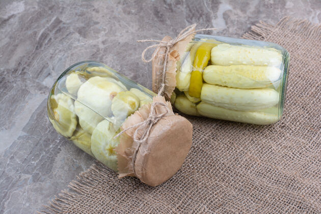 黄瓜两罐各种腌菜放在粗麻布上咸的小吃粗麻布