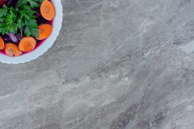 胡萝卜一碗切碎的甜菜根 用胡萝卜片和欧芹叶装饰在大理石上甜菜农产品饮食