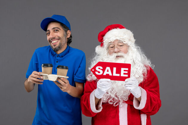圣诞圣诞老人的正面图 男信使拿着售货笔 灰色墙上挂着咖啡服装男快乐